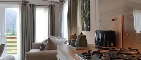Una cocina moderna con estufa a gas, cafetera y vista a un jardín por la ventana.