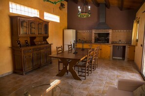 A spacious kitchen with a large wooden table, built-in cabinets, and a brick oven.