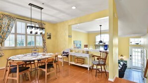 A dining area with a round table, chairs, and a chandelier. There is a kitchen area with a stove and cabinets. - Large 3BR 2.5BA Garage Townhouse in Great West OC Neighborhood with Pool. (Berlin)