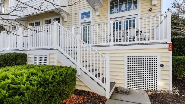 A two-story building with a white exterior, a balcony with outdoor seating, and a visible fire escape. - Large 3BR 2.5BA Garage Townhouse in Great West OC Neighborhood with Pool. (Berlin)