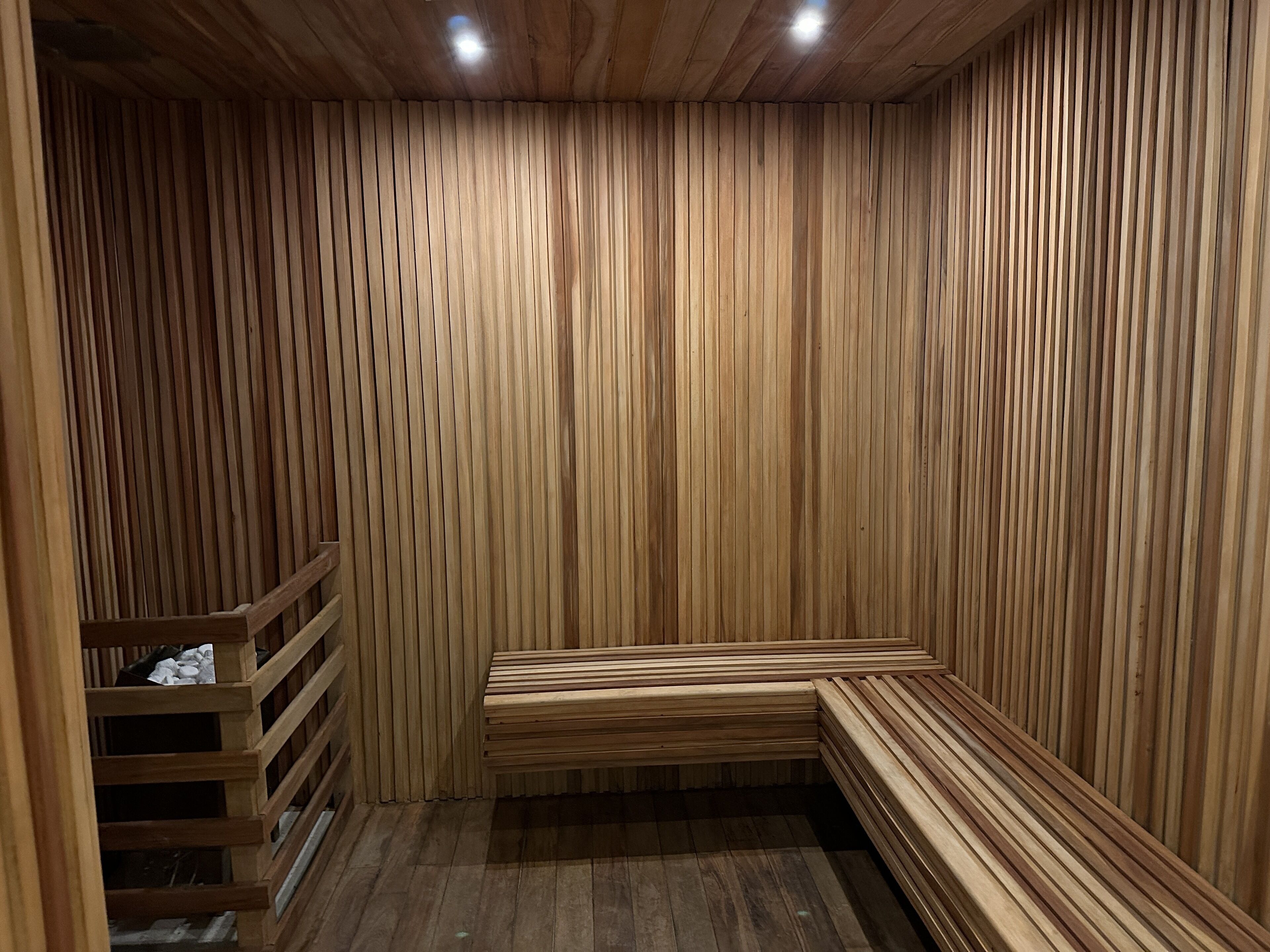 Una sauna con bancos de madera y un banco con respaldo.