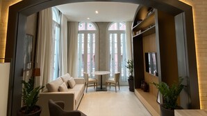 Una sala moderna con un sofá, sillas, una mesita y un televisor.