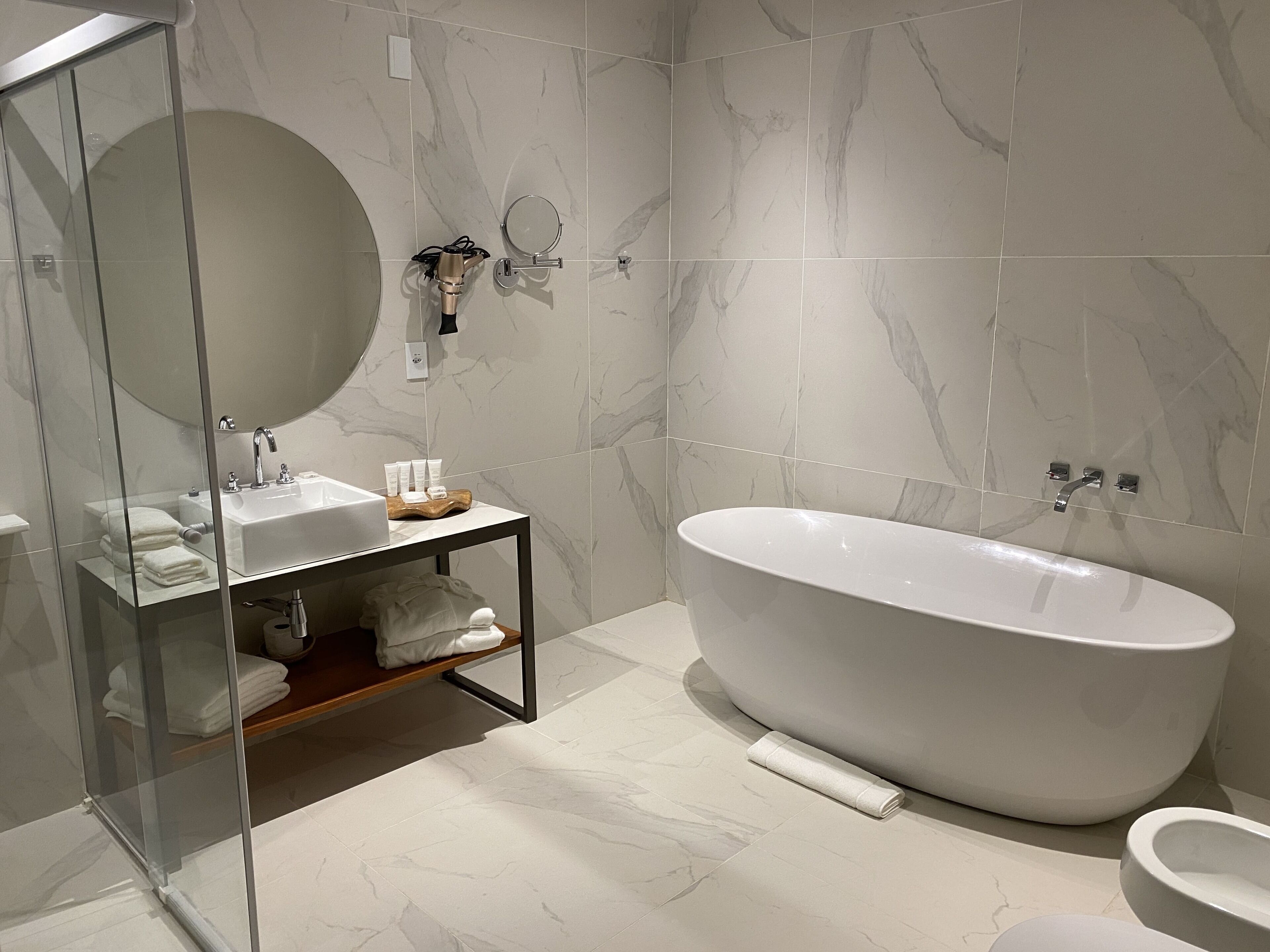 Ein modernes Badezimmer mit freistehender Badewanne, einer Duschkabine und einem Waschtisch mit Spiegel und Waschbecken.