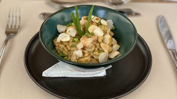 A bowl of food on a black plate with a napkin underneath, placed on a beige tablecloth.