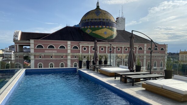 Una piscina en la azotea con vistas a un edificio histórico con cúpula y arcos.