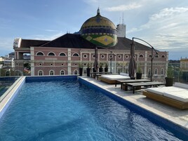 Una piscina al aire libre, sombrillas, sillones reclinables de piscina