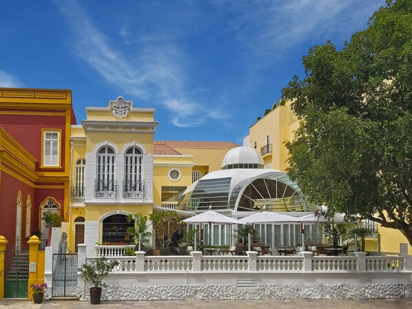 Un edificio con fachada amarilla, balcones blancos y una estructura de cúpula.