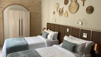 A hotel room with two beds, a brick wall, and decorative woven items on the wall.