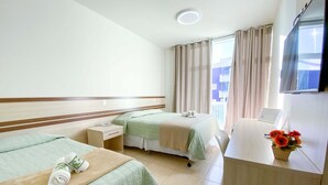 Habitación de hotel con dos camas, un escritorio, una silla, un televisor y una ventana con cortinas.