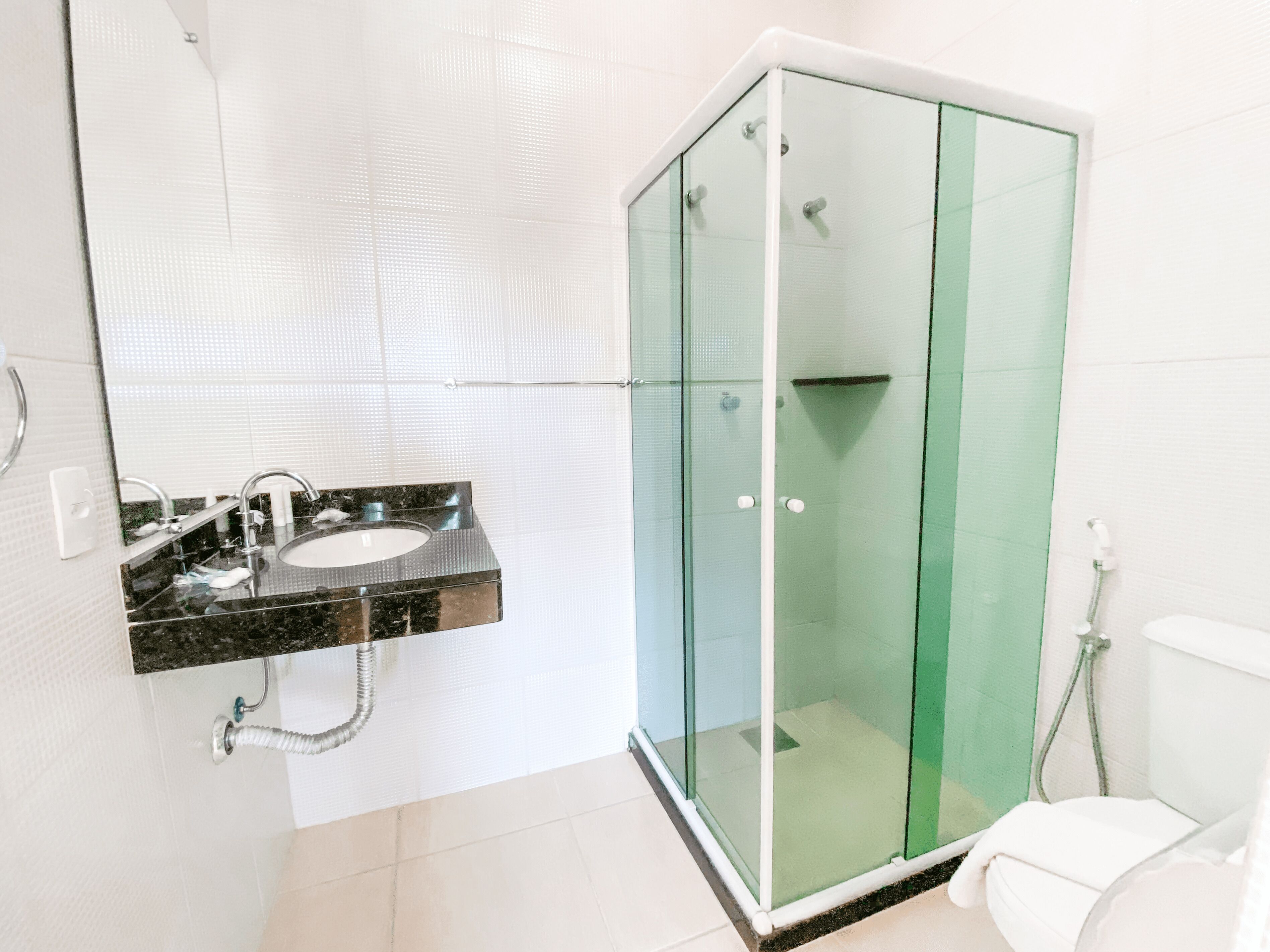 Un baño con ducha de vidrio, lavamanos con encimera de mármol y retrete.