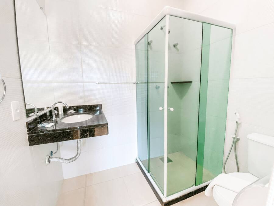 Un baño con ducha de vidrio, lavamanos con encimera de mármol y retrete.