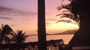 Vista al atardecer con una pérgola de madera y palmeras.