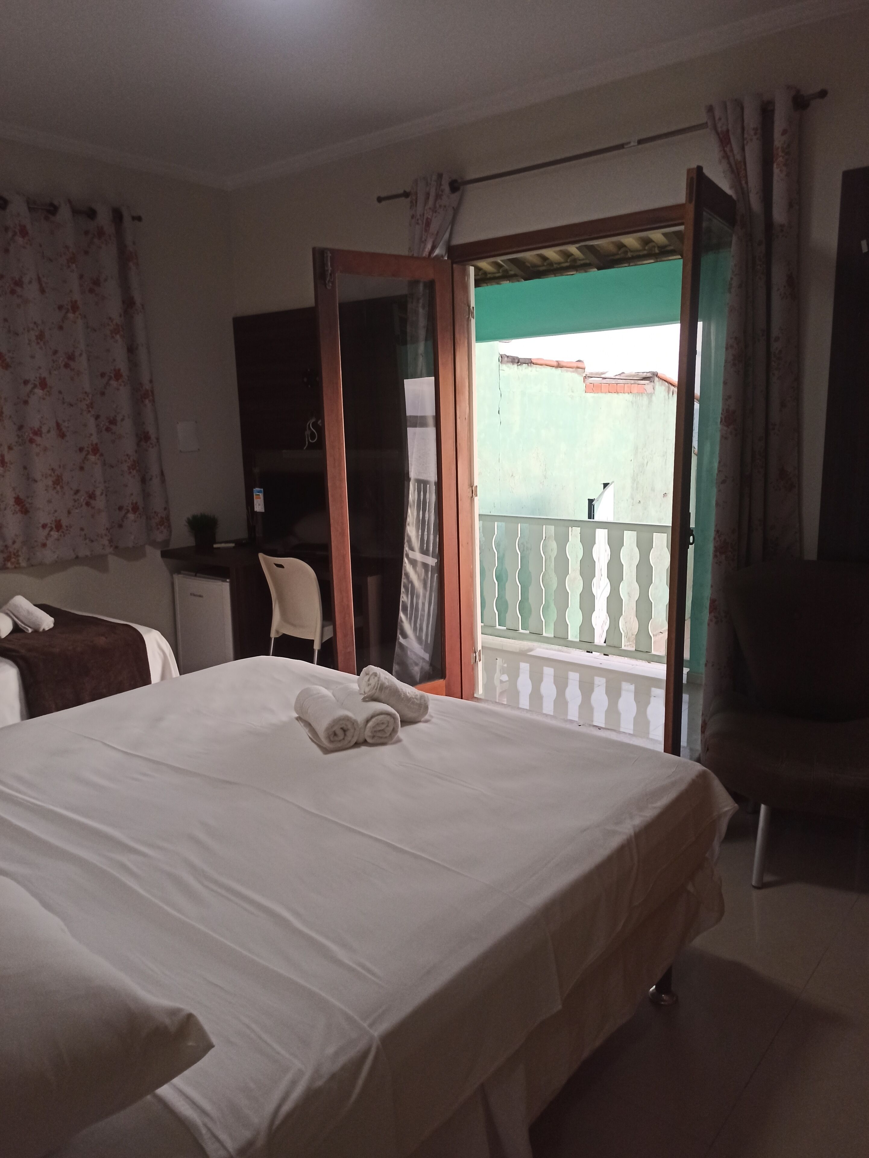 Een hotelkamer met een bed, een stoel, een bureau en een balkon met uitzicht.