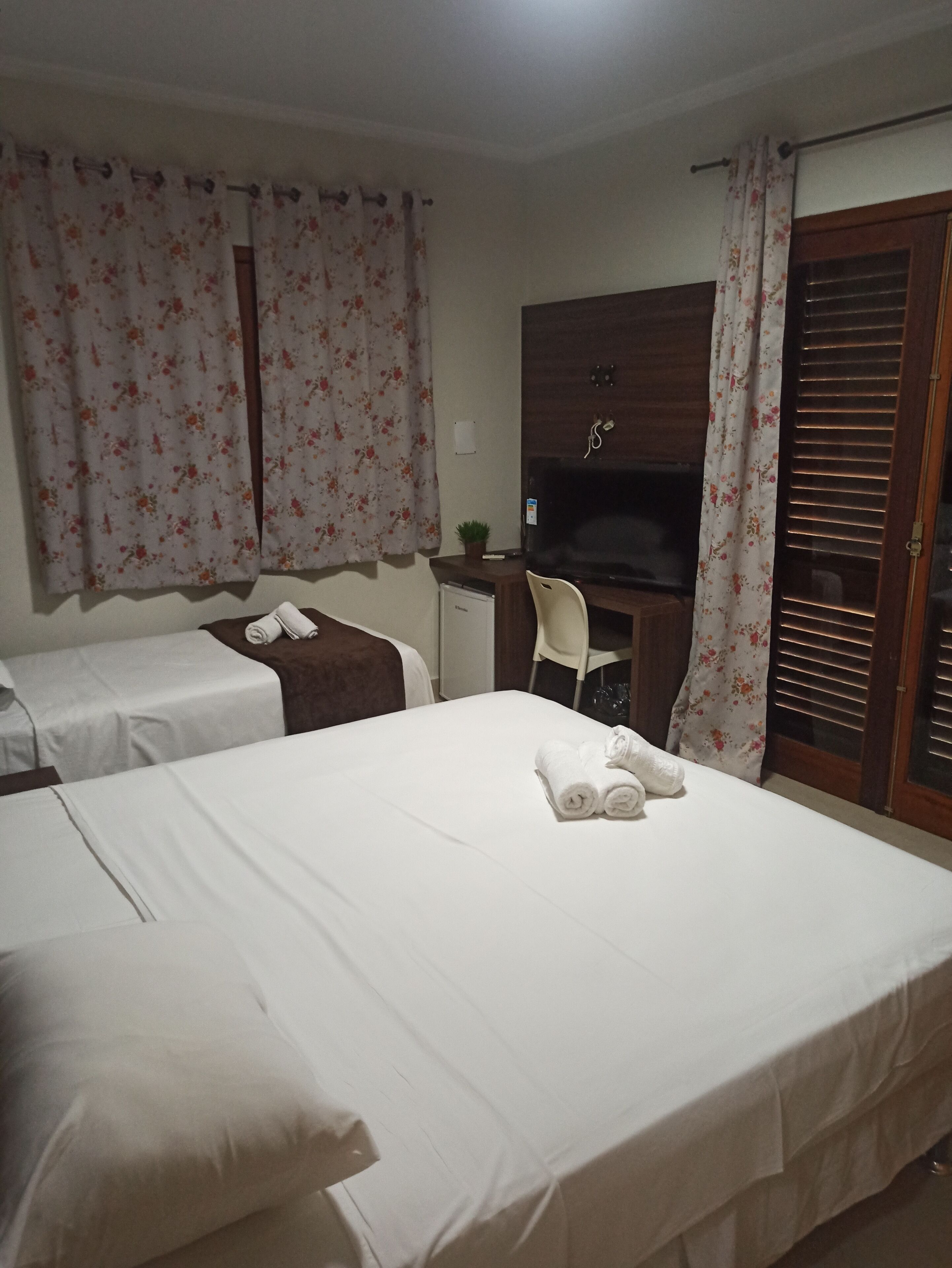 A hotel room with two beds, a desk, a television, and a wardrobe.