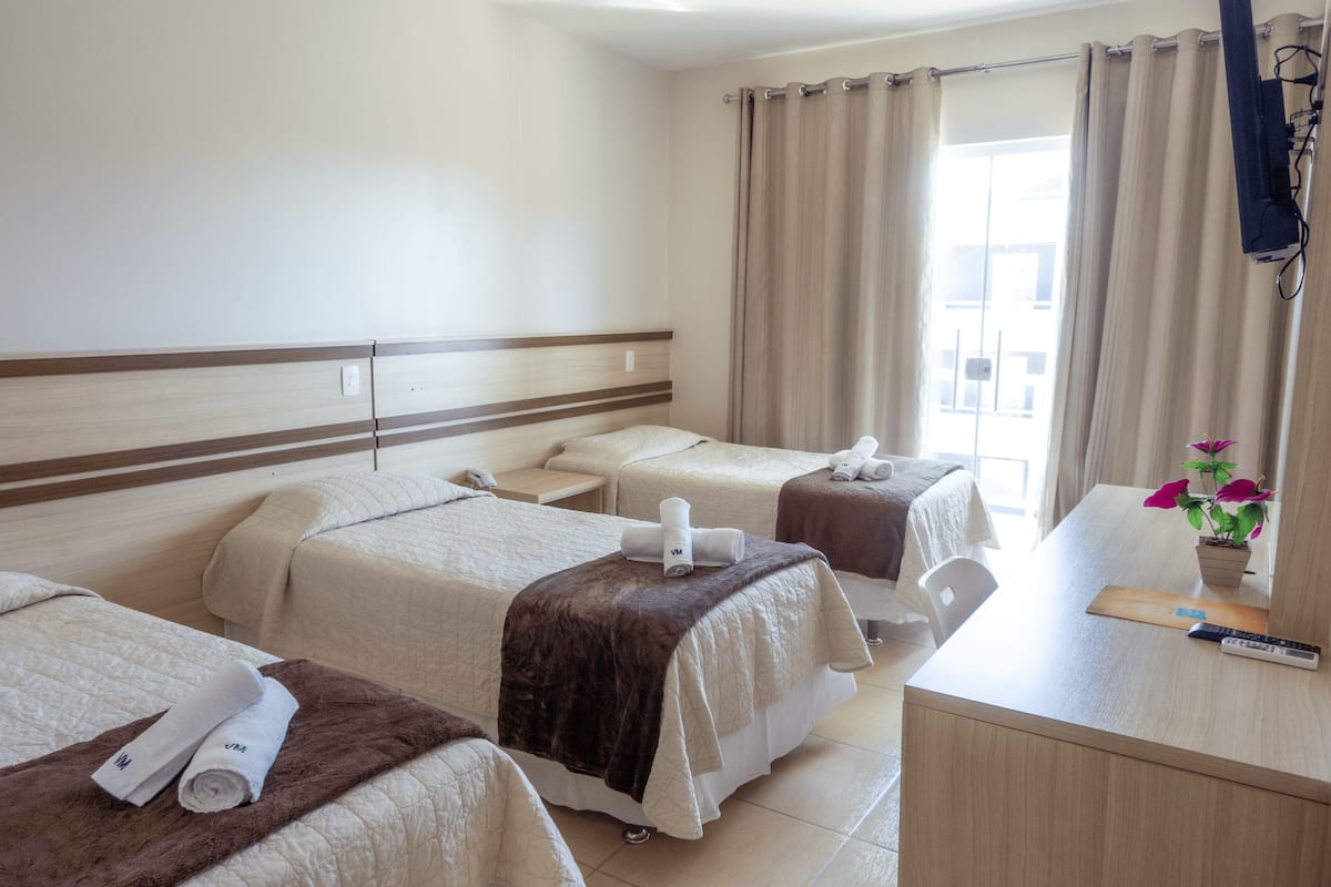 Ein Hotelzimmer mit zwei Betten, einem Schreibtisch und einem Fenster mit Vorhängen.