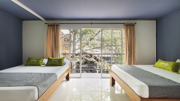 Habitación con dos camas, un ventanal grande y vistas a árboles y un edificio.