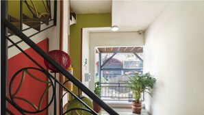 Una escalera con barandillas metálicas, una pared roja y una planta en maceta en el rellano.