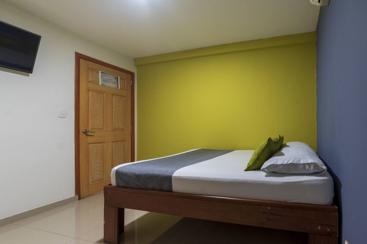 Une chambre à coucher avec un lit en bois, un oreiller vert et un oreiller blanc.