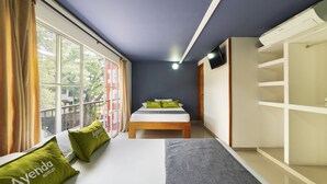 Habitación de hotel con cama, armario, ventana con cortinas y vista a árboles.