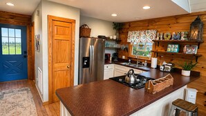 A kitchen with a central island, wooden cabinets, a refrigerator, and a window with a view.