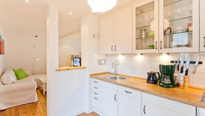 Une cuisine moderne avec des meubles blancs, un plan de travail en bois et une machine à café.