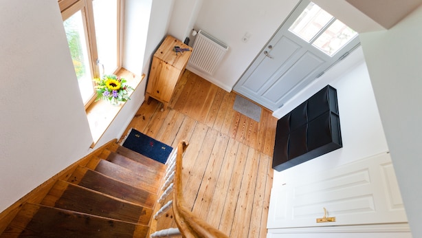 Un escalier en bois menant à un palier où se trouvent un radiateur et une porte.