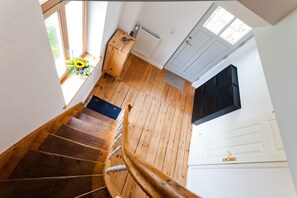 Un escalier en bois menant à un palier où se trouvent un radiateur et une porte.