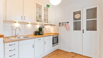 A kitchen with white cabinets, a wooden countertop, a sink, a stove, and a hanging light fixture.