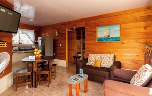 A wooden-paneled living room with a dining area, a sofa, and a television. - Cozy Home Emanuel in La Fortuna - WIFI, TV, A / C (La Fortuna)