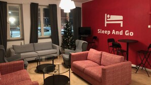 A modern living room with a red wall, grey sofa, red armchairs, a glass coffee table, and a Christmas tree. - Sleep And Go (Harnosand)