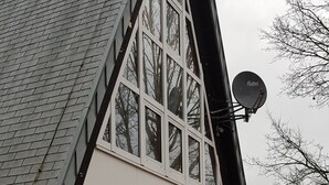 A modern house with a sloped roof, large windows, and a satellite dish.