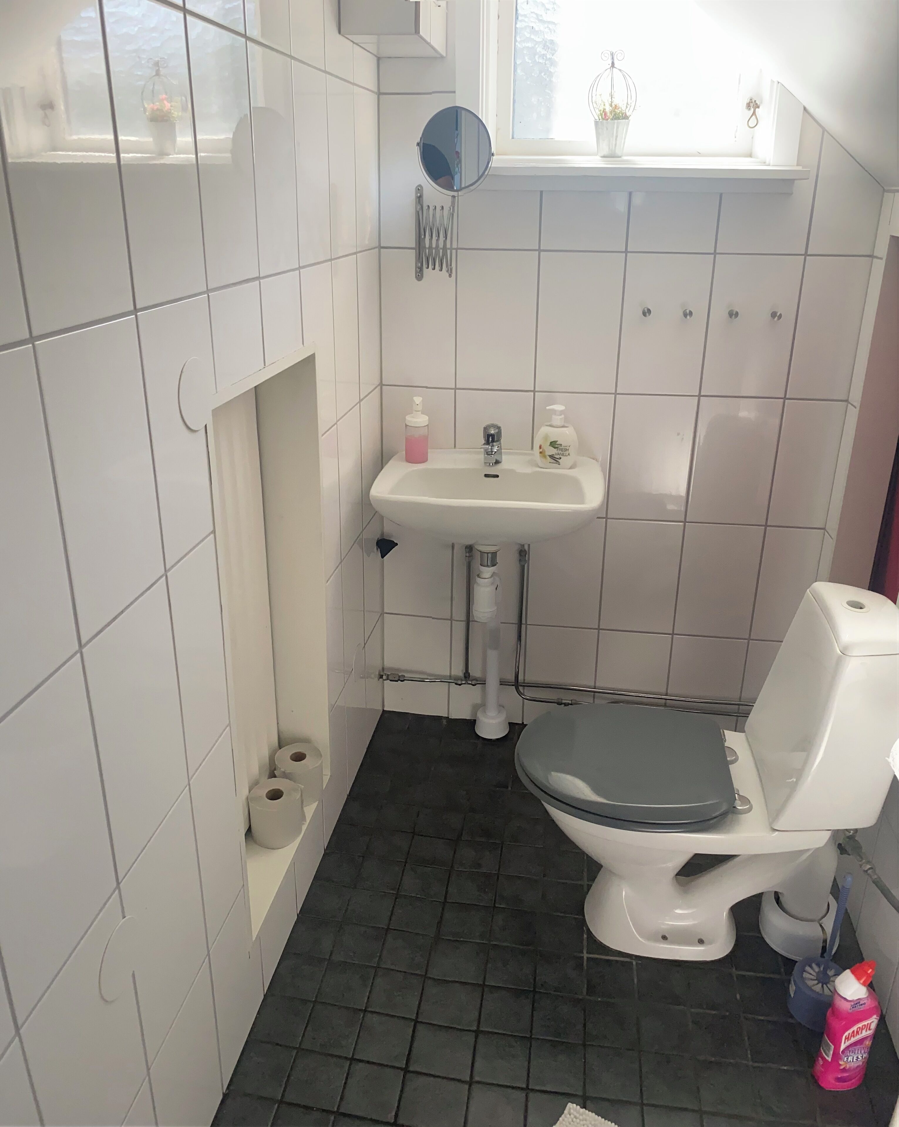 Ein kleines Badezimmer mit Toilette, Waschbecken und einem Fenster über dem Waschbecken.