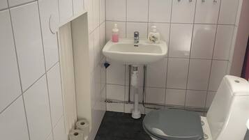 Ein kleines Badezimmer mit Toilette, Waschbecken und einem Fenster über dem Waschbecken.