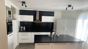 A modern kitchen with white cabinets, a black countertop, and a built-in oven.