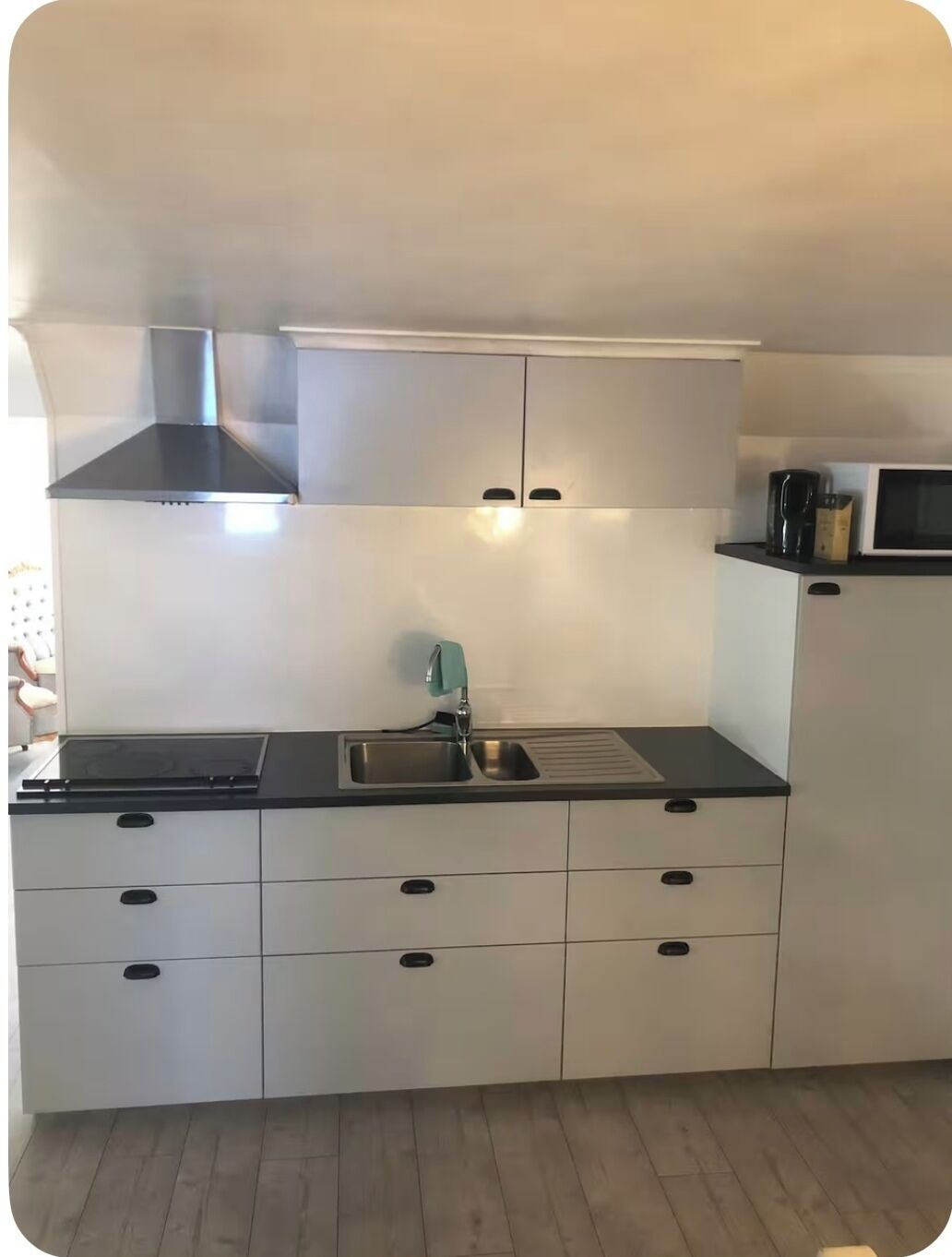 A modern kitchen with a stainless steel range hood, a double sink, and a microwave.