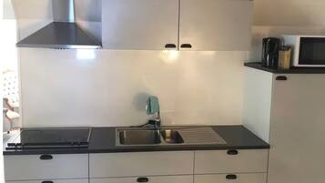 A modern kitchen with a stainless steel range hood, a double sink, and a microwave.