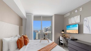 Ein modernes Hotelzimmer mit einem großen Bett, einem Schreibtisch, einem Sessel und einem Fernseher.