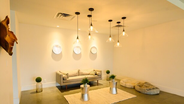 A modern living room with a sofa, pendant lights, a rug, and decorative items. - Orlando Vacation Rooms (Kissimmee)