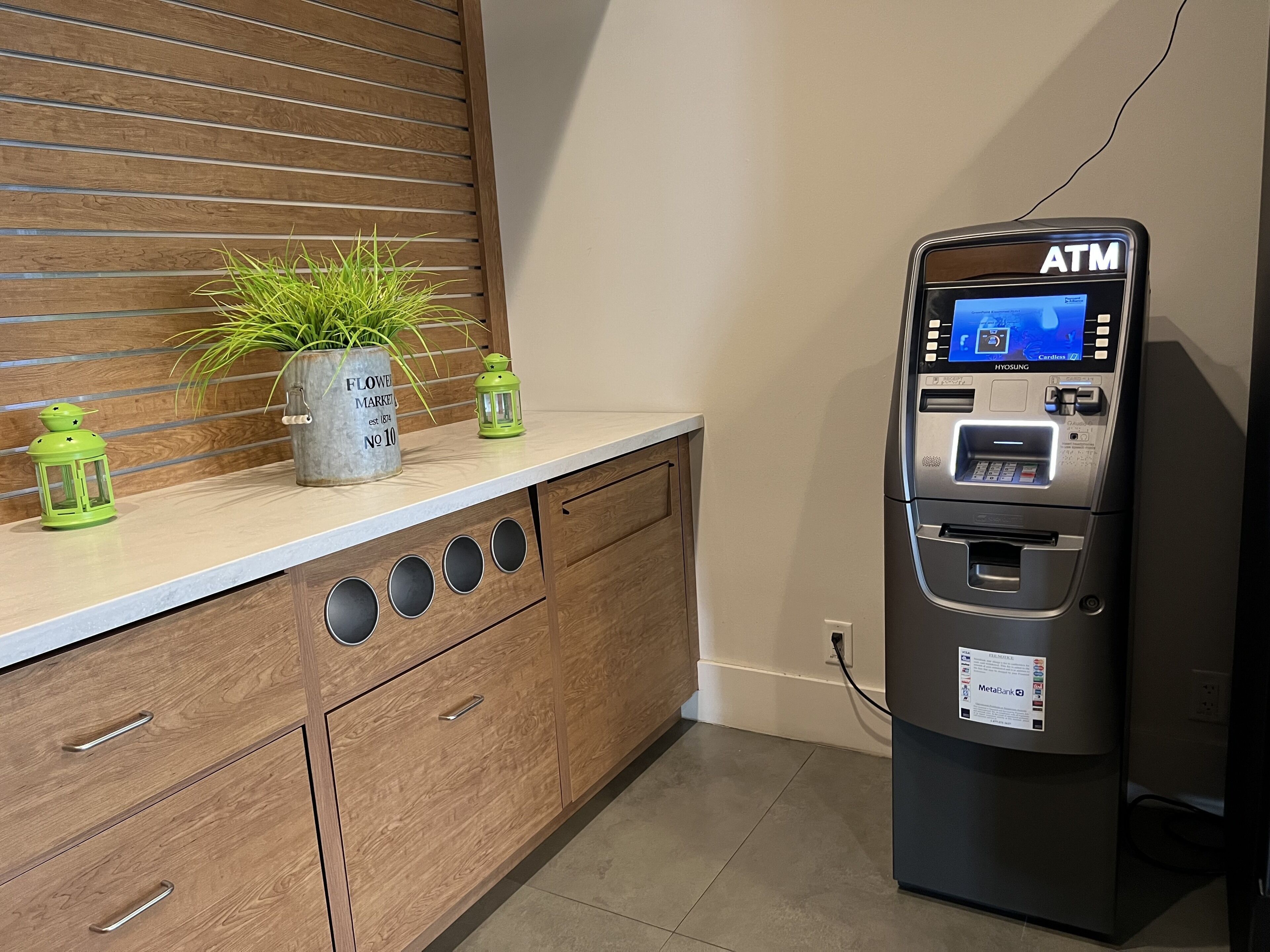 A modern kitchen with wooden cabinets, a countertop, and an ATM machine.