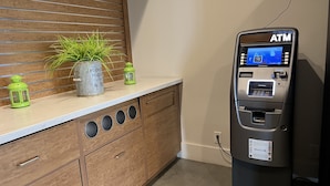 A modern kitchen with wooden cabinets, a countertop, and an ATM machine. - Orlando Vacation Rooms (Kissimmee)