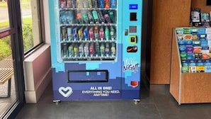 A vending machine with a variety of snacks and drinks, a heart logo, and the text 'ALL IN ONE! EVERYTHING YOU NEED. ANYTIME!' - Orlando Vacation Rooms (Kissimmee)