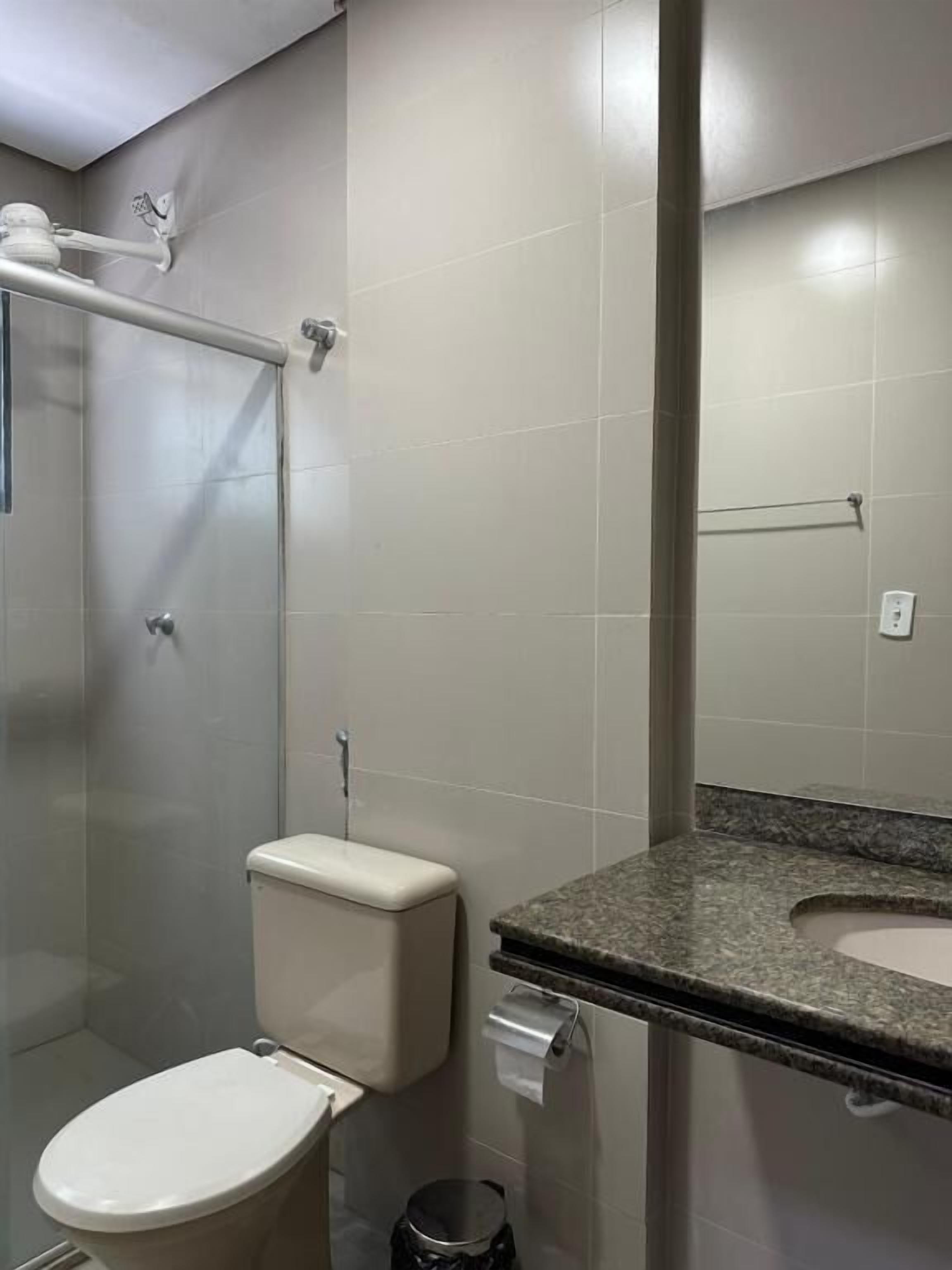 A bathroom with a toilet, a shower, and a sink.