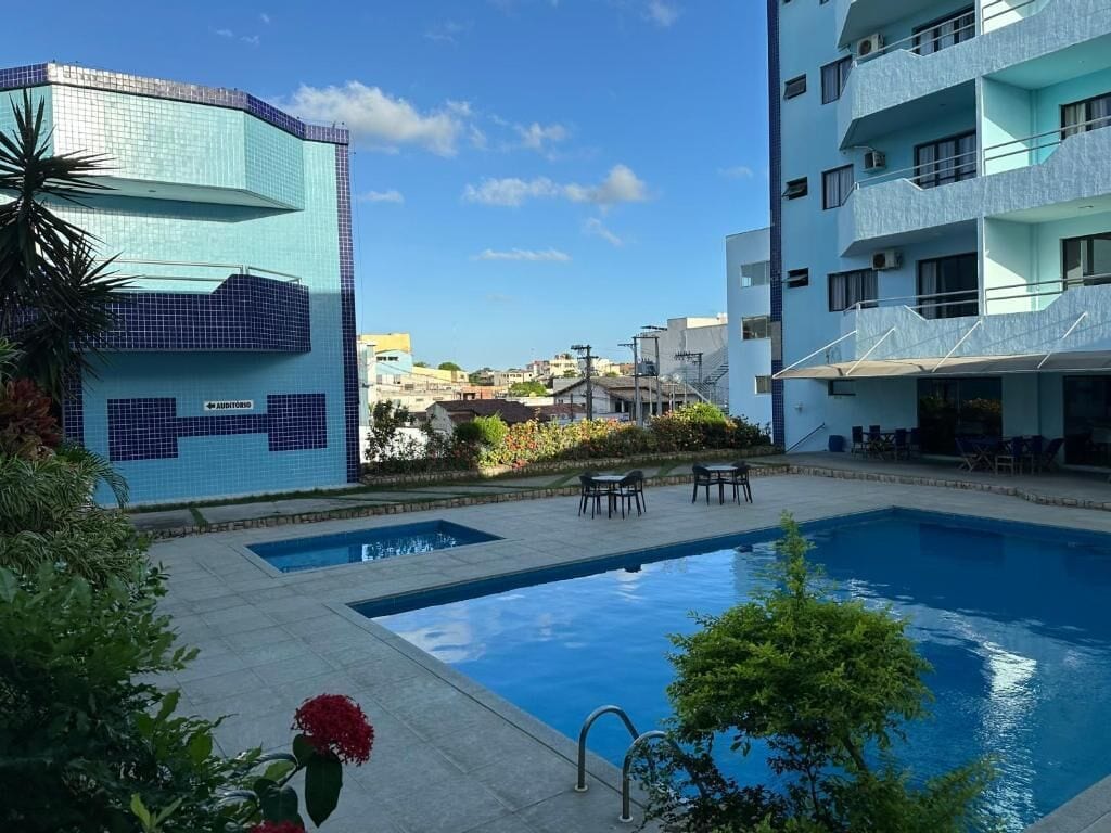 Una piscina con vista despejada a los edificios circundantes y un pequeño jardín.