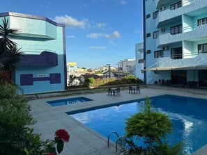 Piscina com vista desobstruída dos edifícios ao redor e um pequeno jardim.