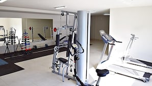 Un gimnasio con diversos equipos de ejercicio, incluyendo una cinta de correr, máquinas de pesas y una jaula para sentadillas.