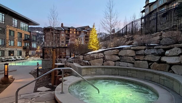 Uma área de spa com hidromassagem, paredes de pedra e piscina.