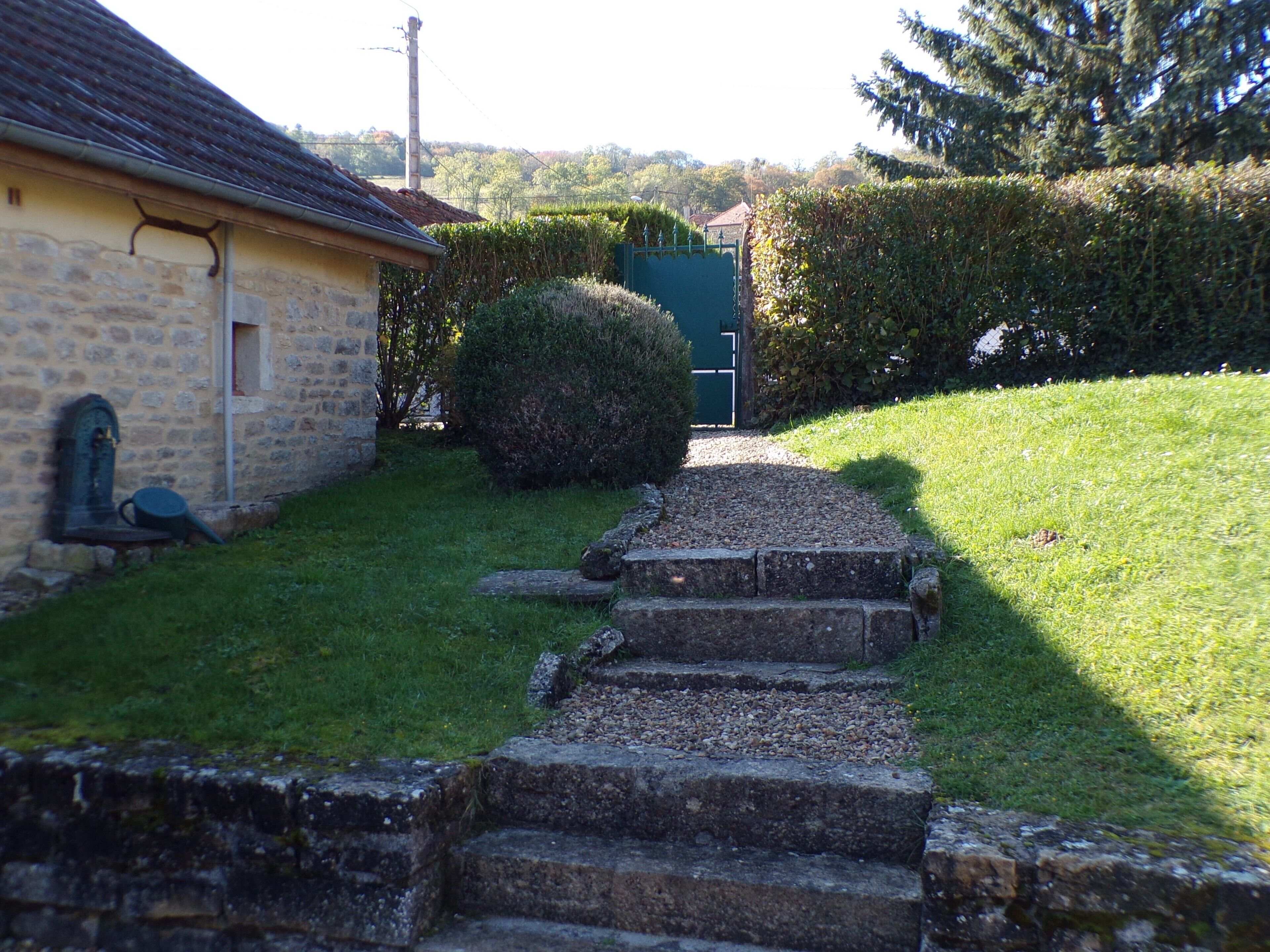 A stone staircase leading to a house with a tiled roof and a stone wall.