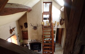 Un interior rústico con una escalera de madera, una chimenea y varias cabezas de animales colgadas en las paredes.