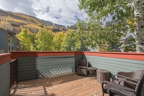 Enjoy the serene mountain views from this deck, featuring a wicker seating area and a small table.