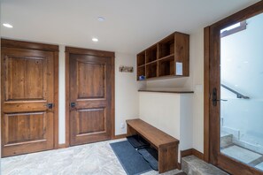 Enter a welcoming space with double doors, a bench, and shelving.